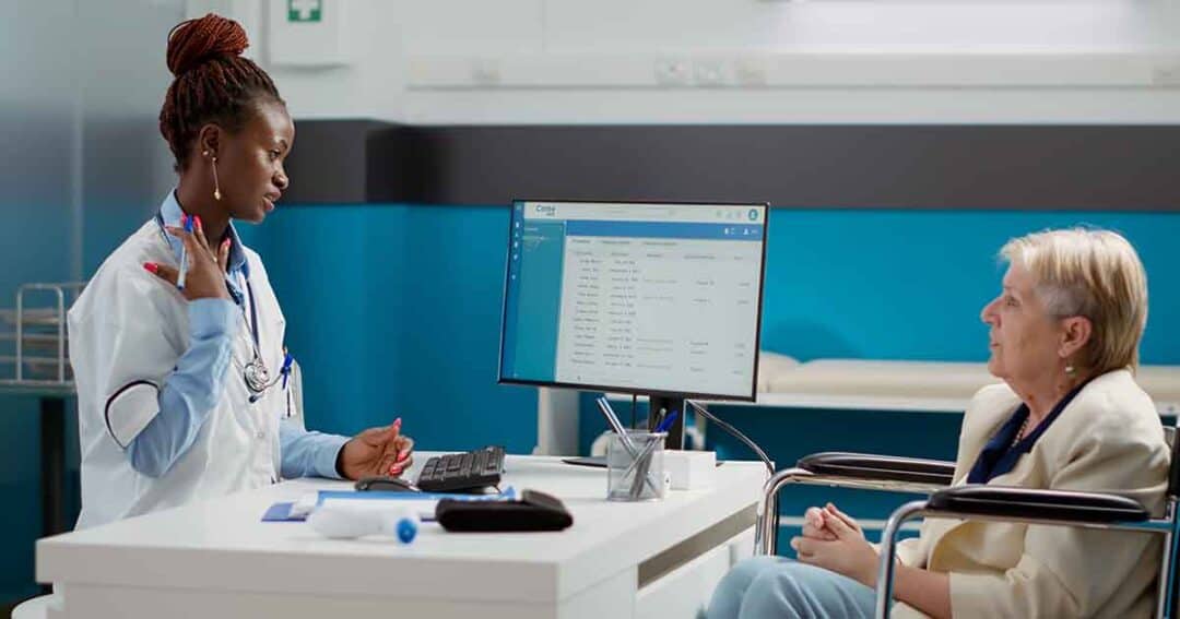 African american doctor doing checkup visit with female wheelchair user, talking about physical disability and healthcare diagnosis. Consulting woman with impairment at medical appointment.
