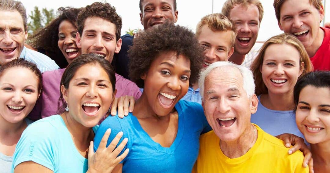 a large group of people of different colors and ages smiling for a photo