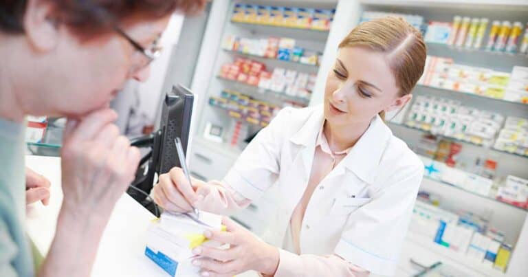 Pharmacist explaining the cost of the drugs to a woman at the counter.