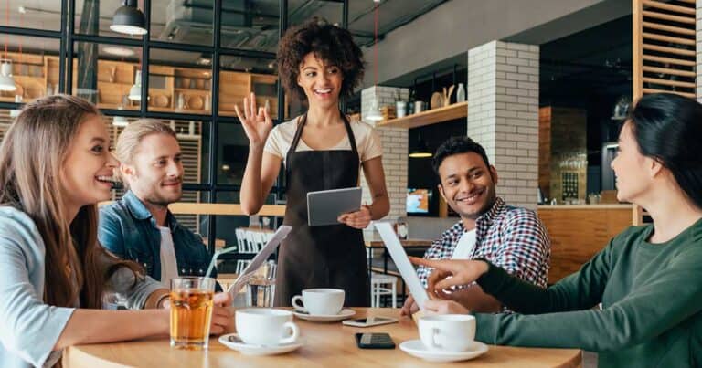 Woman at restaurant, with her friends, asking the waitress for allergen friendly foods from the menu.