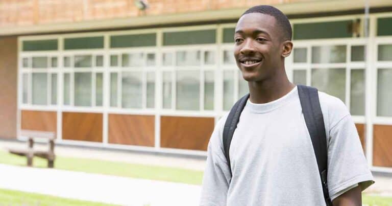 young male college student standing in front of school