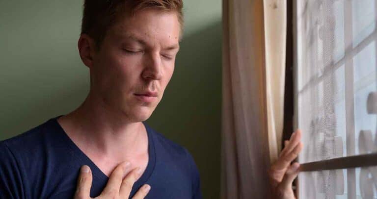 Portrait of young man having asthmatic attack at home