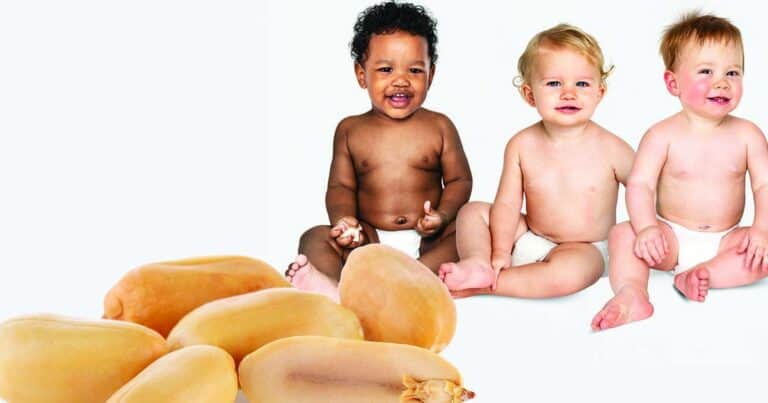 Three babies in diapers sit side by side, smiling, against a plain background. In the foreground, there is a close-up image of peanuts.