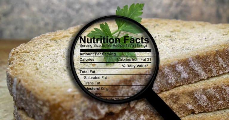 A magnifying glass focuses on the nutrition facts label over slices of bread, highlighting information such as calories, fat, and cholesterol content. A sprig of parsley rests on top of the bread.